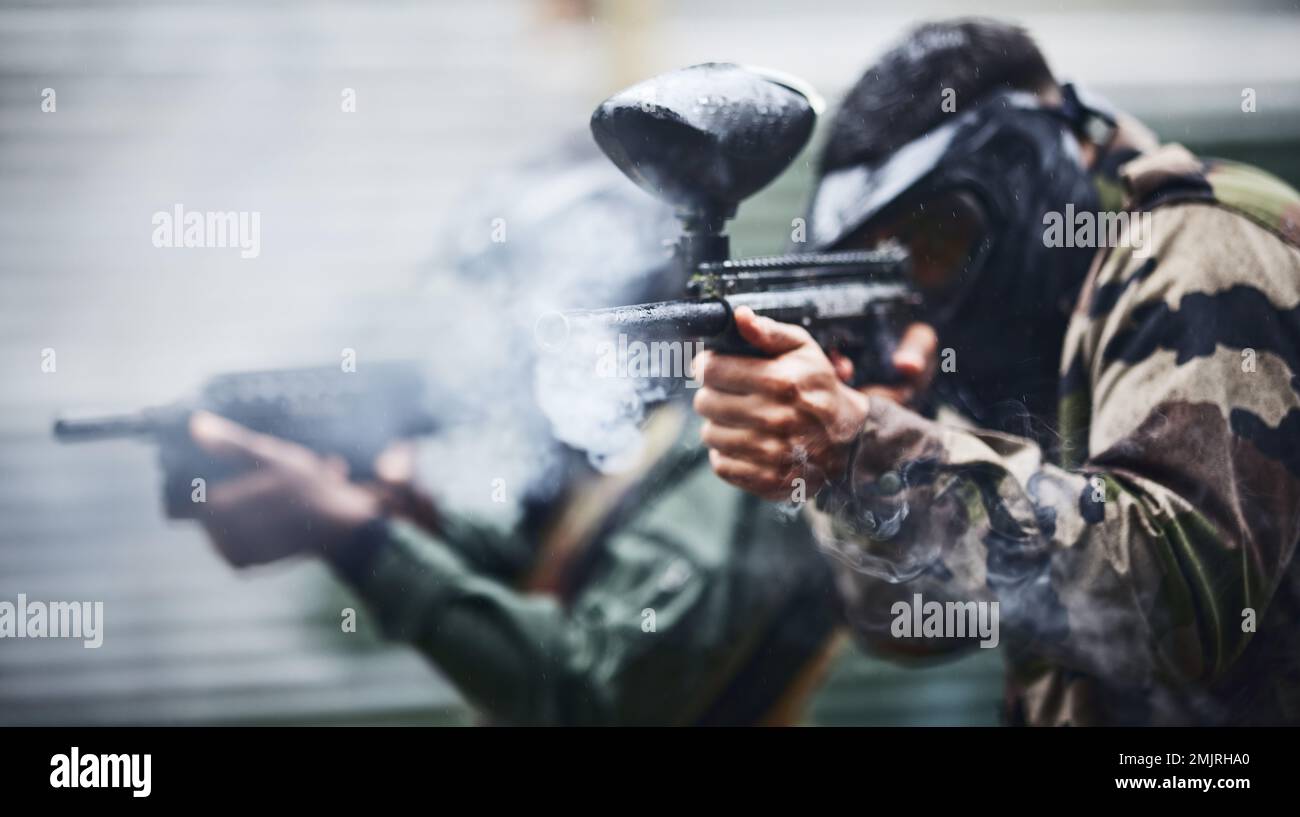 Paintball, Sport und Rauch mit Schießpistole, Action und militärisches Schlachtfeld mit Soldat, Krieg und Fitness im Freien. Leute zusammen Stockfoto