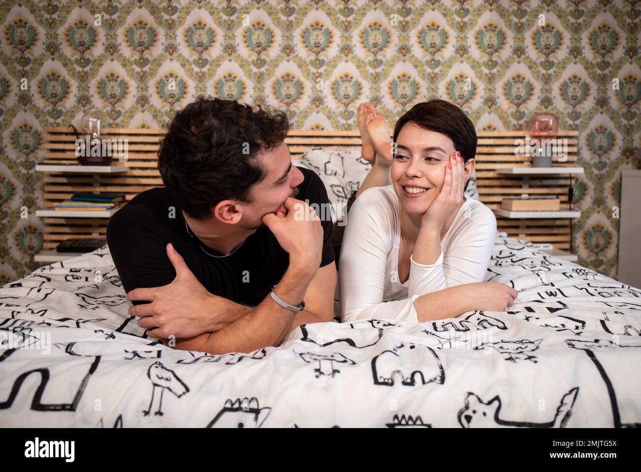 Das junge Paar liegt auf dem Bett und schaut sich in die Augen. Konzept von Liebe und Glück. Stockfoto