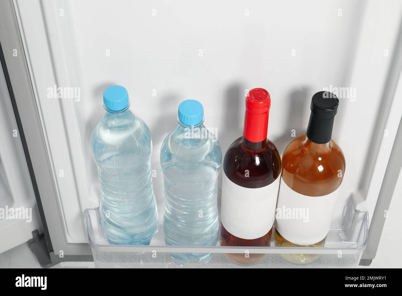 Flaschen Wasser und Wein auf dem Regal im Kühlschrank Stockfoto