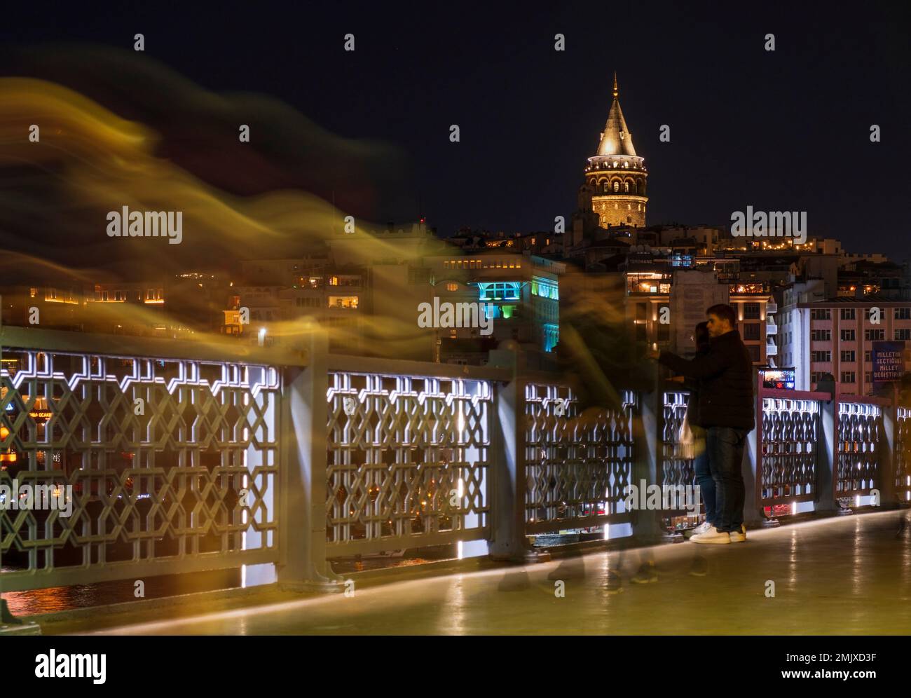 Istanbul, Türkei, 01.19.2023: Menschen, die nachts auf der Brücke spazieren gehen und im Hintergrund den Galata-Turm. Langzeitbelichtung Istanbul Nachtleben. Istanbul Stockfoto