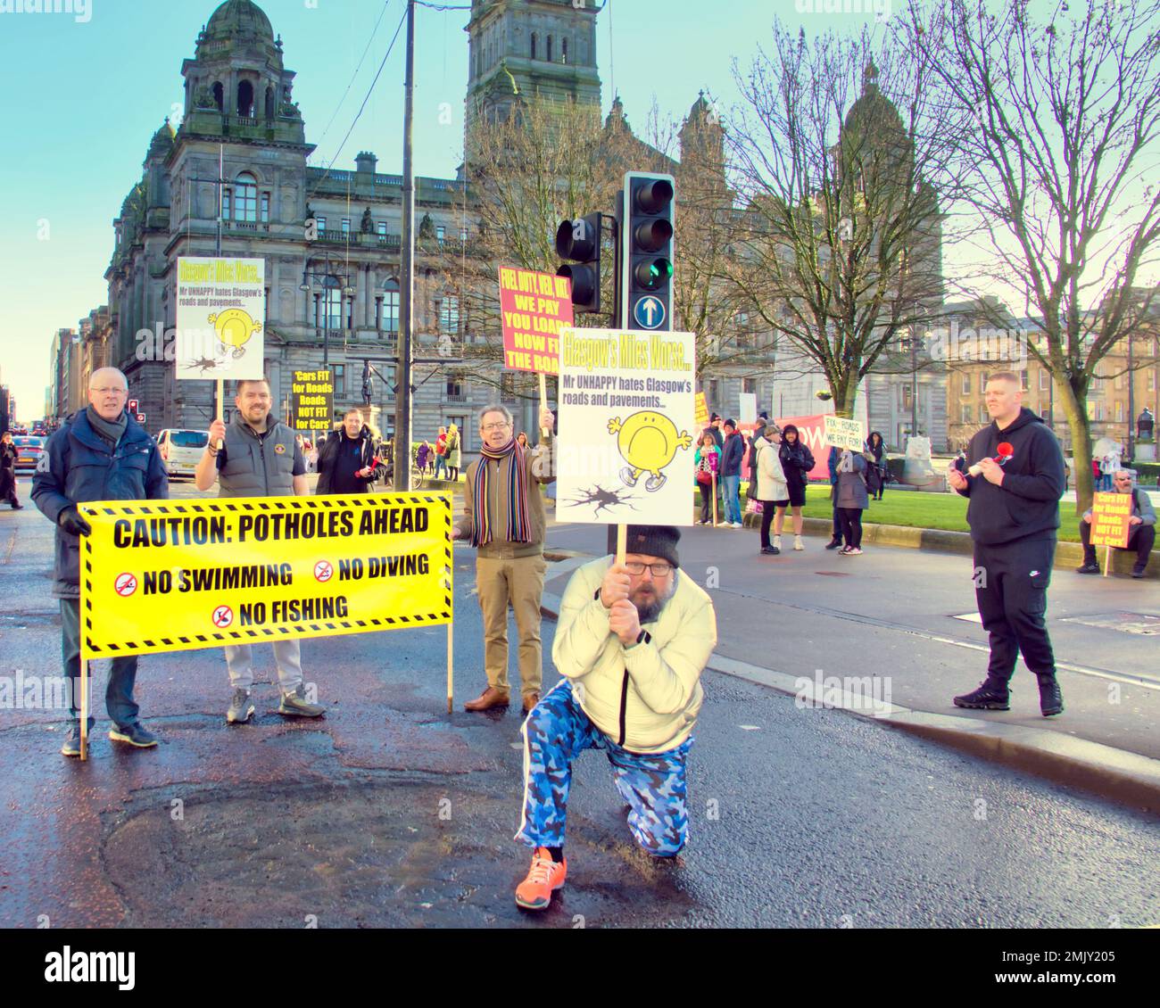 Glasgow, Schottland, Vereinigtes Königreich 28. Januar 2023. Schlagloch-Protest vor dem hauptquartier des rates auf dem george Square sah, wie eine große Menge Plakate Demonstranten mit einem von der Menge finanzierten Banner winkten und die Zustimmung von vorbeifahrenden Autofahrern erhielten, als sie am Straßenrand mit einem großen Schlagloch posierten. Credit Gerard Ferry/Alamy Live News Stockfoto