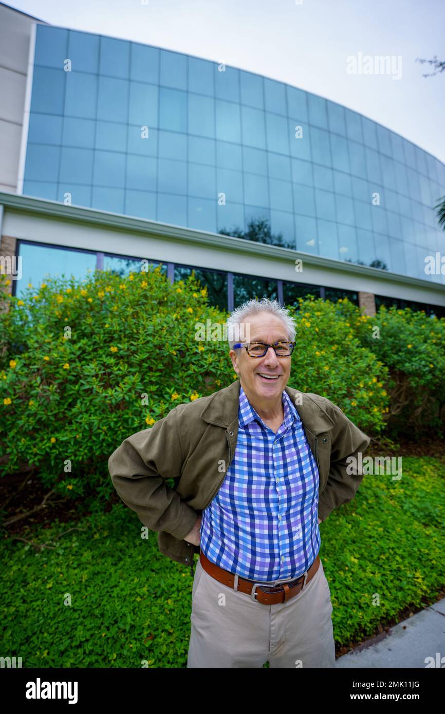 Ein hübscher Senior-Mann, der vor einem Bürogebäude posiert Stockfoto