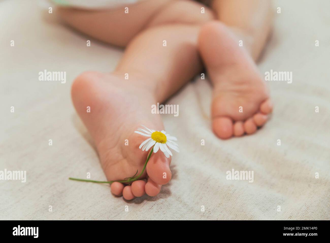 Schlafendes Baby, das eine Kamille mit dem Fuß hält Stockfoto