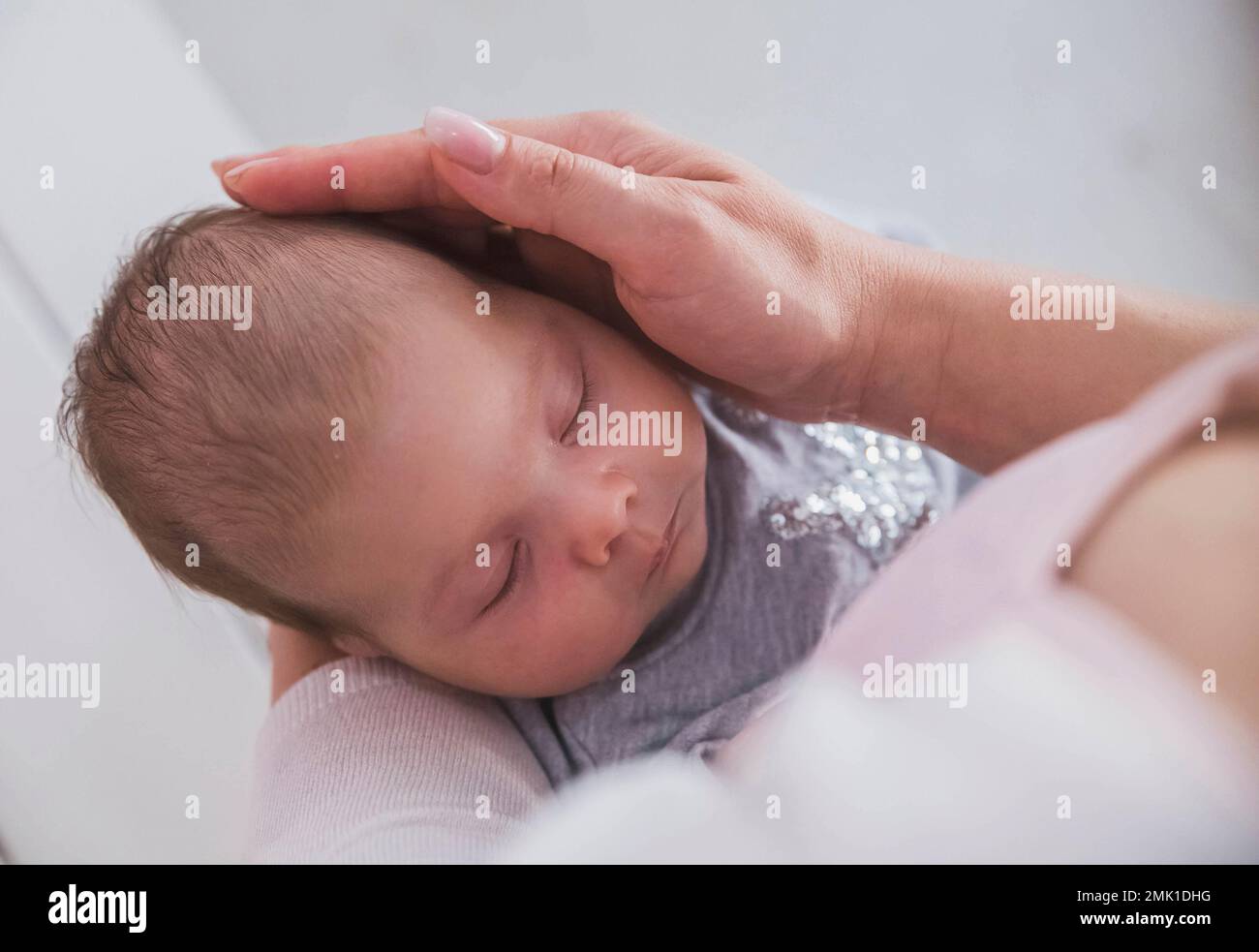 Mutter hält das Baby in den Armen und streichelt seinen Kopf Stockfoto