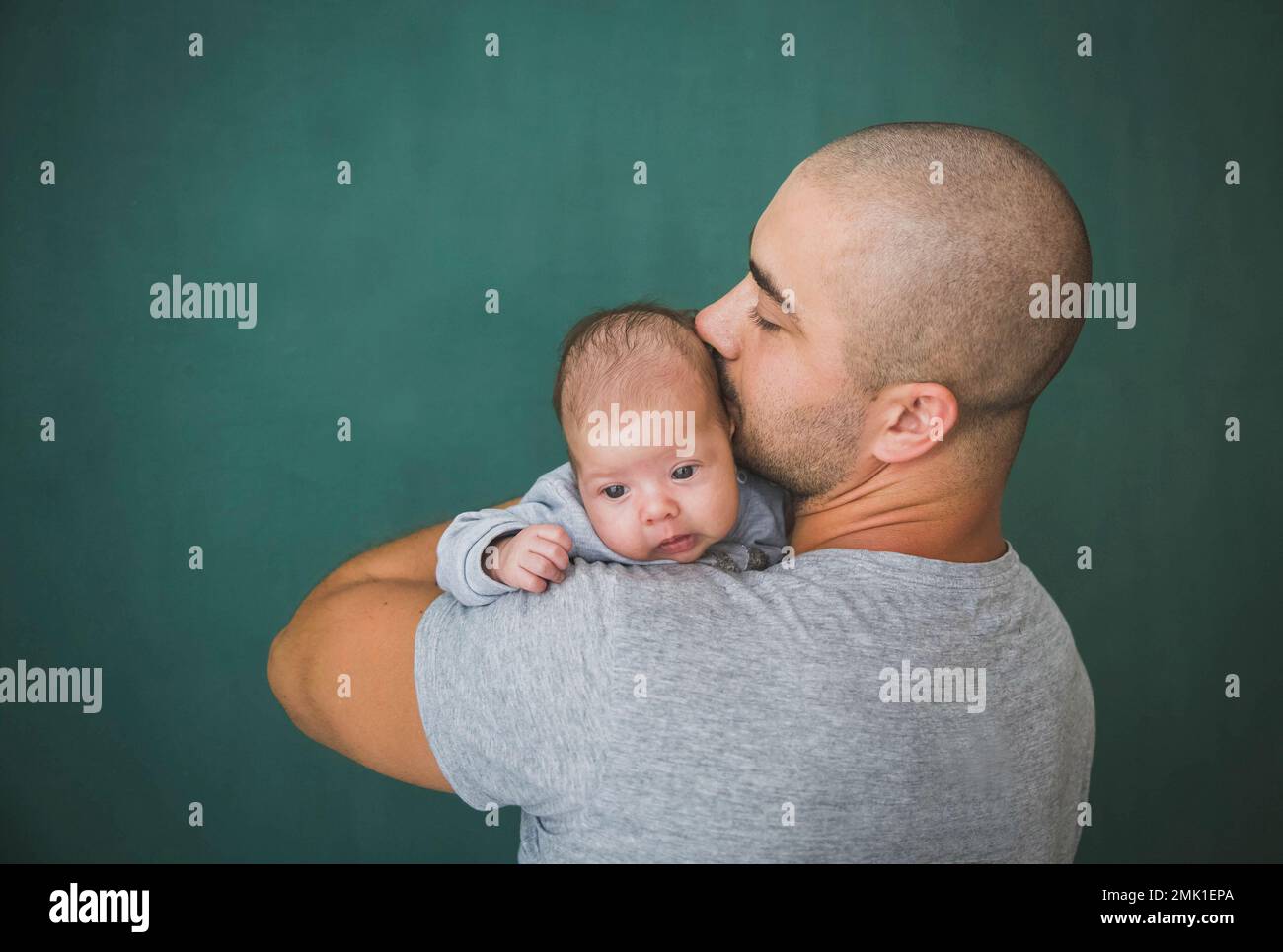 Junger Vater mit kurzen Haaren küsst seine neugeborene Tochter Stockfoto