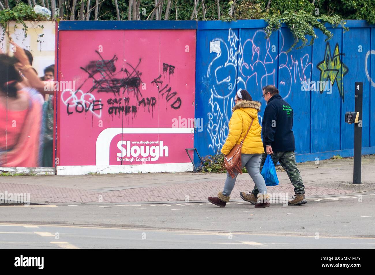 Slough, Berkshire, Großbritannien. 28. Januar 2023. Ein paar gehen an Graffiti vorbei und sagen den Leuten, sie sollen sich lieben und nett sein. Slough in Berkshire durchläuft einen gewaltigen Wandel. Die Gebäude werden abgerissen und sollen durch weitere Wohnungen ersetzt werden. Kredit: Maureen McLean/Alamy Live News Stockfoto