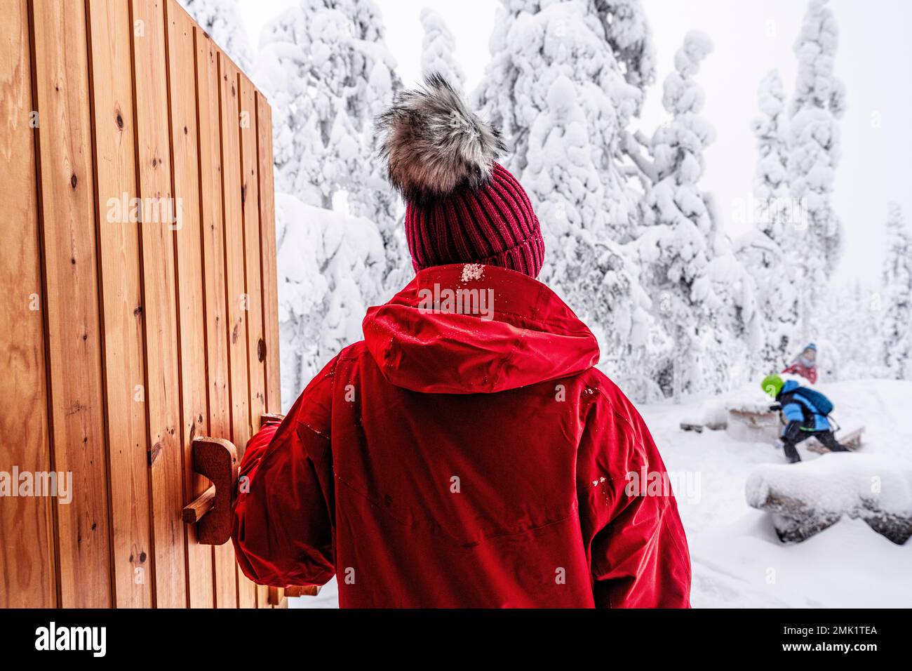 Rückansicht einer Frau, die ihre glücklichen Kinder beim Spielen im Schnee ansieht, ISO Syote, Nordostrobothnia, Lappland, Finnland Stockfoto
