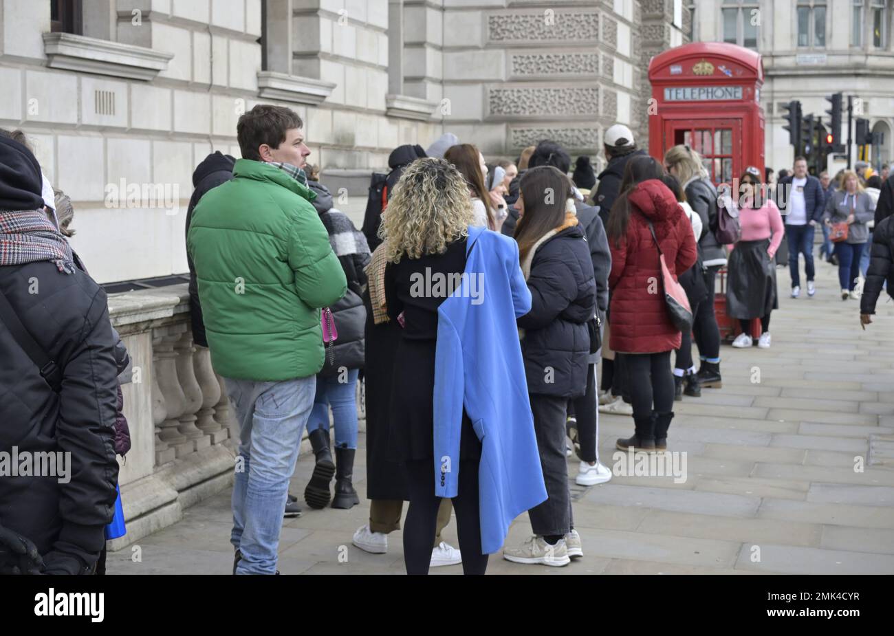London, England, Großbritannien. Touristen, die sich anstellen, um von einem der berühmten roten Telefonboxen am Parliament Square, Westminster, fotografiert zu werden. Stockfoto