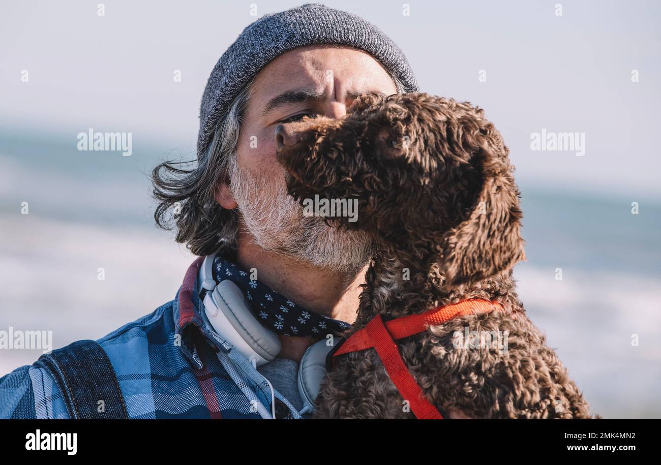 Ein Typ umarmt seinen Hund draußen. Der niedliche Wasserhund in den Armen seines Besitzers. Stockfoto