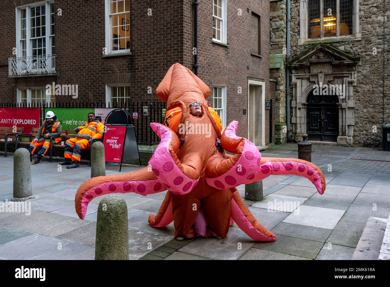 Eine junge Frau in einem Squid-Kostüm, die durch die City of London, London, Großbritannien läuft. Stockfoto