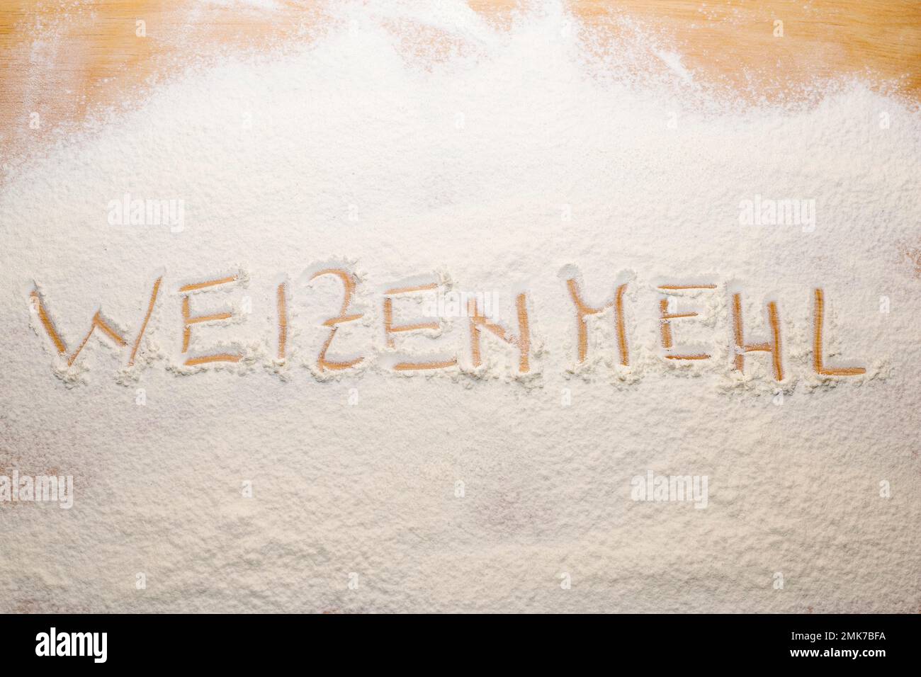 Das Wort Weizenmehl wurde in Mehl auf einem Nudelbrett geschrieben Stockfoto