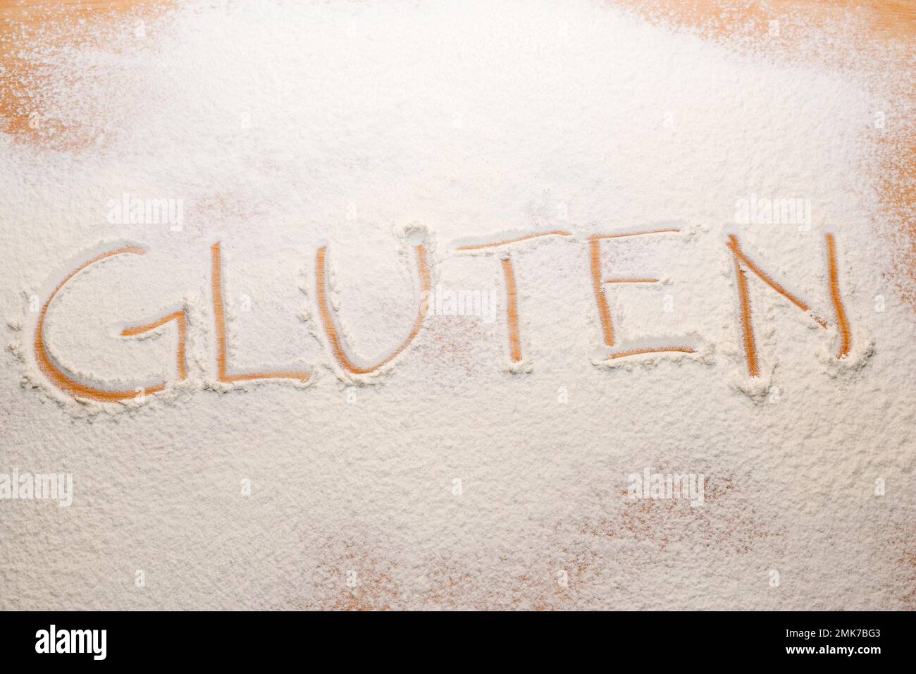 Das Wort Gluten stand im Mehl auf einem Nudelbrett Stockfoto