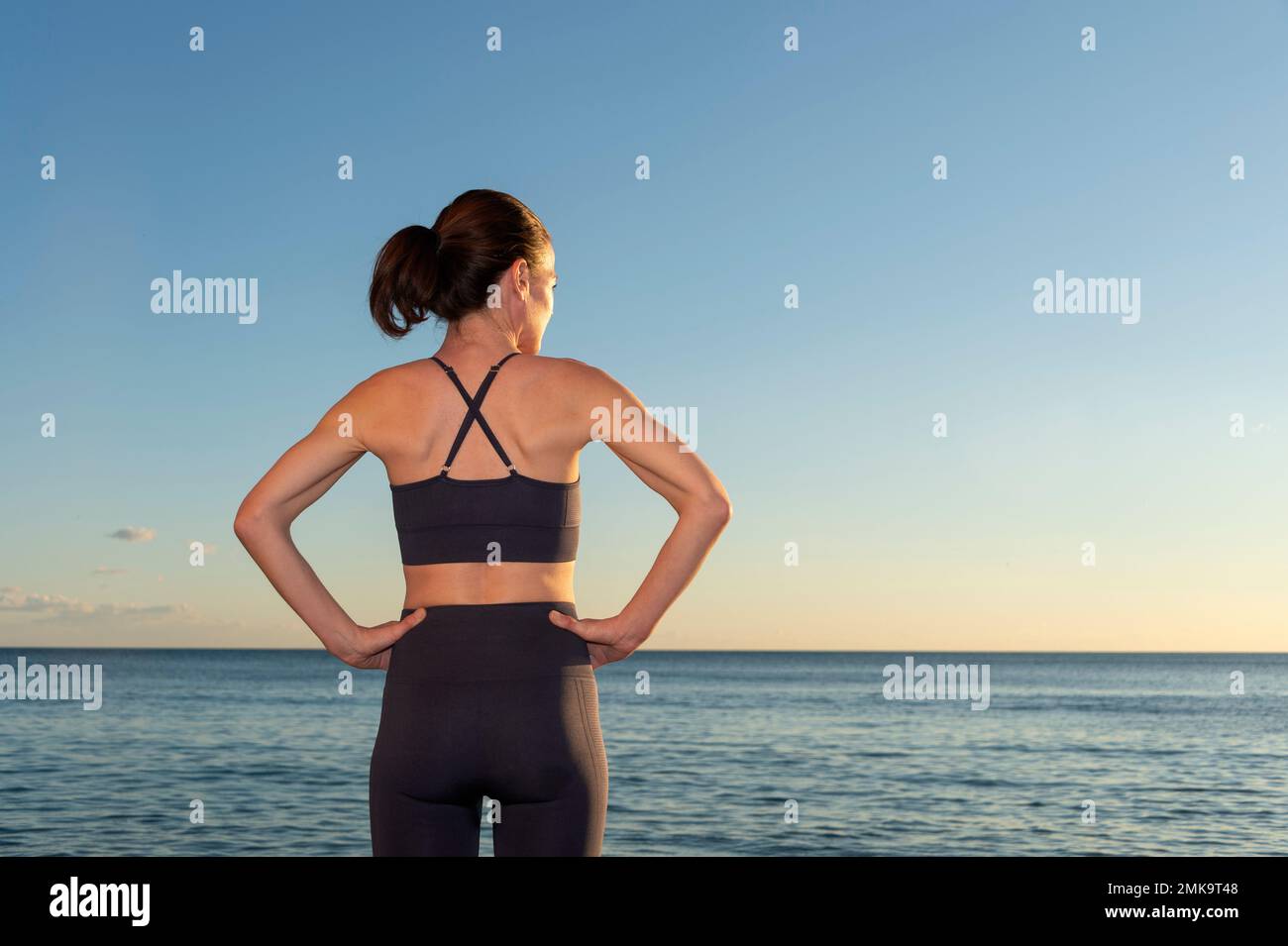 Fit für Damen mit Händen an der Hüfte und Blick auf das Meer in Sportbekleidung. Entspannung nach dem Training. Stockfoto