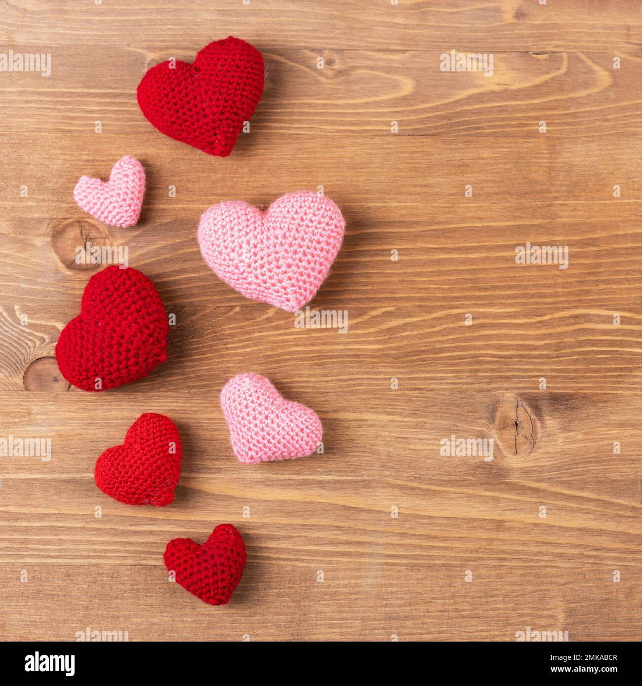 Bunte rosa Strickherzen auf Holzhintergrund. Grußkarte zum Valentinstag, Muttertag und Geburtstag. Stockfoto