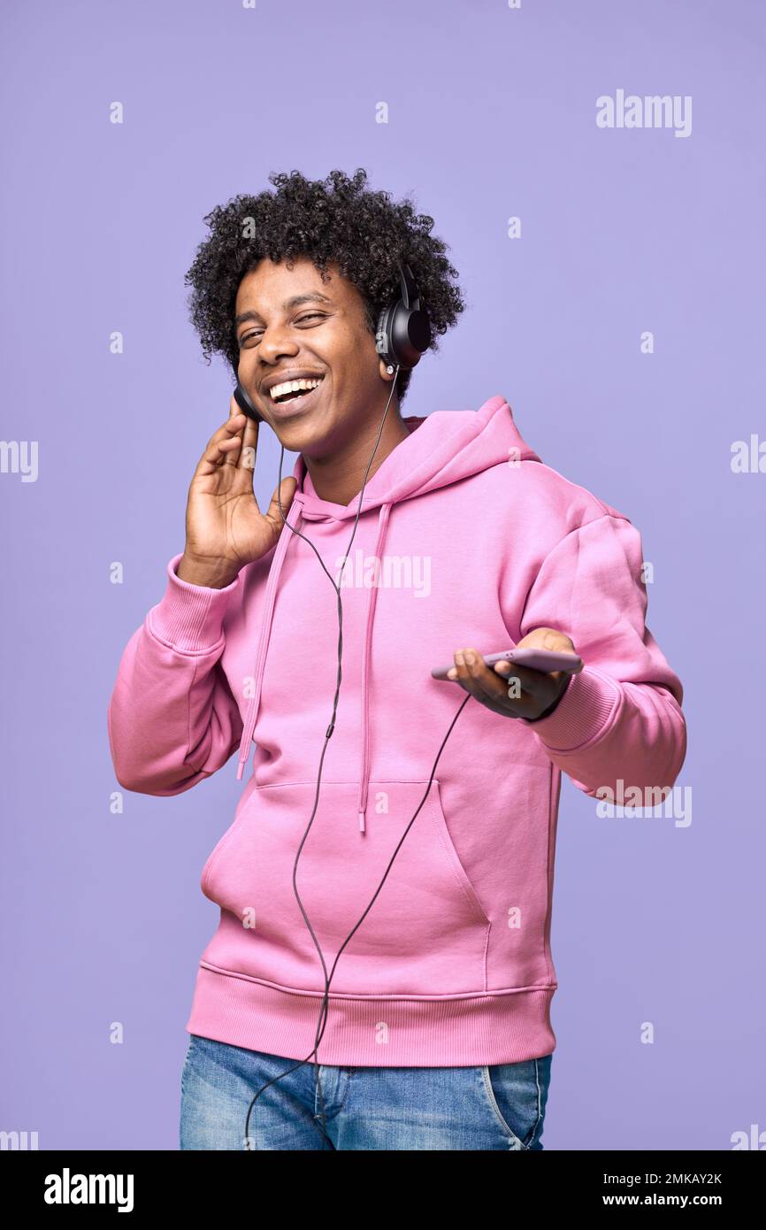 Glücklicher afrikanischer Teenager, der Kopfhörer trägt und Musik mit dem Mobile tanzt. Stockfoto