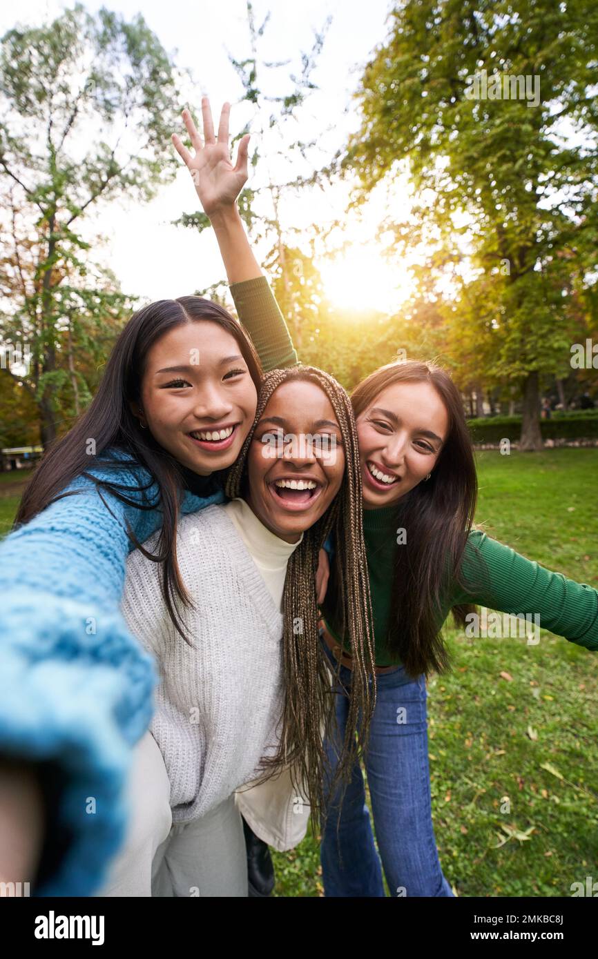 Vertikales Porträt von drei Mädchen außerhalb, die Selfie-Freundschaft in multiethnischen Gruppen aufnehmen Stockfoto