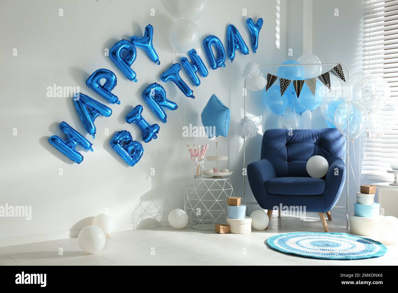 Phrase HAPPY BIRTHDAY aus blauen Ballonbuchstaben im dekorierten Zimmer Stockfoto