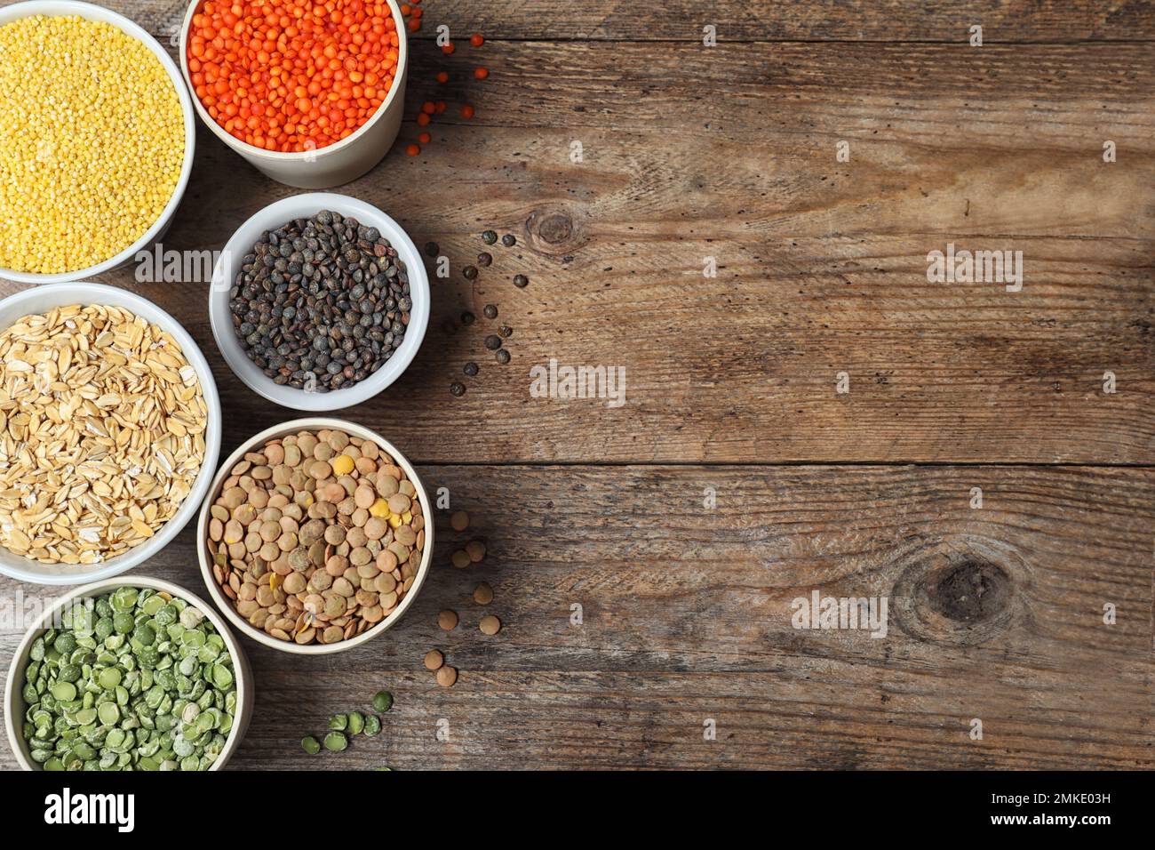 Flache Liegezusammensetzung mit verschiedenen Arten von Hülsenfrüchten und Getreide auf Holztisch, Platz für Text. Organische Körner Stockfoto