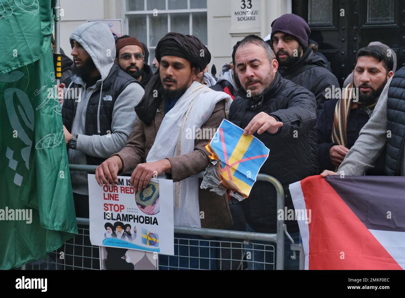London, Großbritannien. 28. Januar 2023 Ein Demonstrant verbrennt ein Bild der schwedischen Flagge. Muslimische Demonstranten haben sich versammelt, um die Schändung des Koran durch den rechtsextremen Politiker Rasmus Paludan anzuprangern - durch Verbrennung und Edwin Wagensveld in den Niederlanden, der den heiligen Text zerrissen hat. Das ursprüngliche Feuer des dänisch-schwedischen Paludan wurde vor der türkischen Botschaft in Stockholm durchgeführt, und die schwedische Regierung versuchte, sich von der Demonstration zu distanzieren. Kredit: Elfte Stunde Fotografie/Alamy Live News Stockfoto