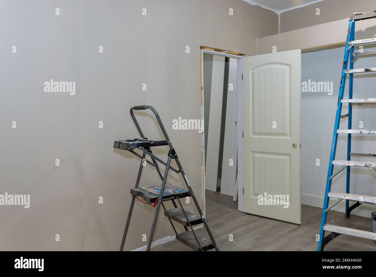 Die Wände wurden in einem leeren Raum gestrichen, mit Malerausrüstung und einer Treppenleiter neben dem leeren Raum Stockfoto