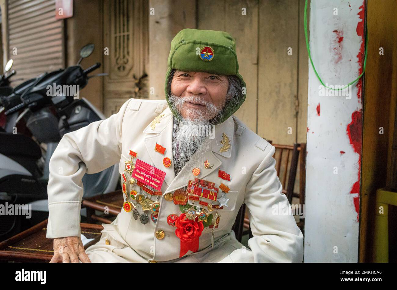Ein älterer vietnamesischer Militärveteran zeigt stolz seine Kriegsmedaillen, während er in einer Straße im Zentrum von Hanoi, Vietnam, sitzt. Stockfoto