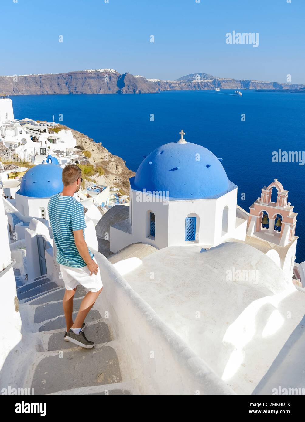 Junge Männer Touristen besuchen Oia Santorini Griechenland an einem sonnigen Tag im Sommer mit weißen Häusern und Kirchen, griechische Insel Ägäische Kykladen Stockfoto
