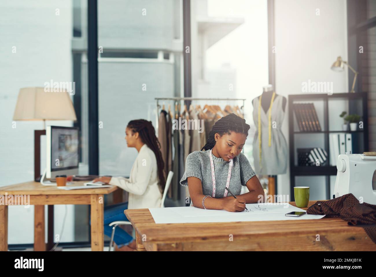 Die Konstruktion erfordert viel Zeit und Konzentration. Eine erfolgreiche junge Modedesignerin, die an ihrer neuesten Kreation arbeitet. Stockfoto