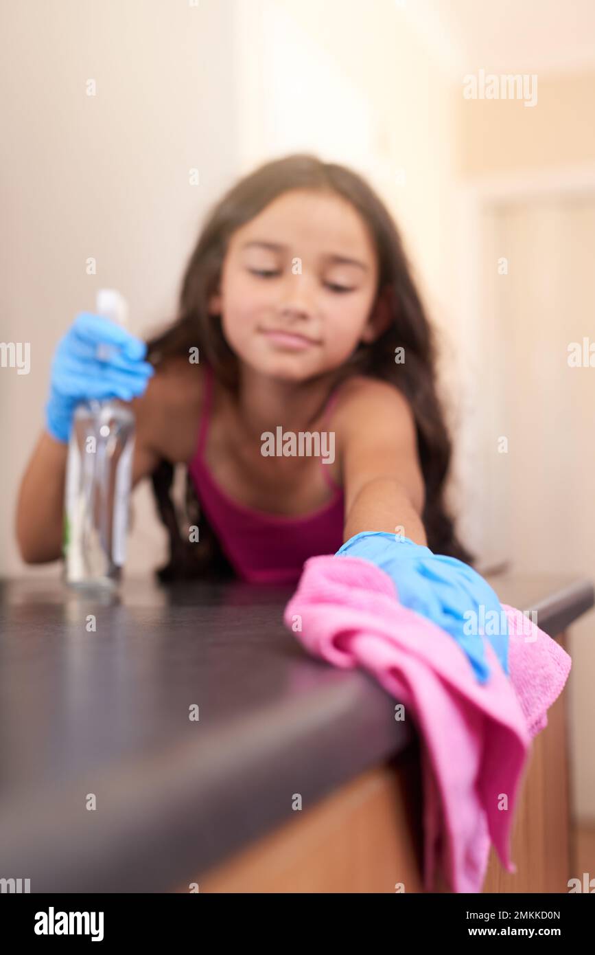 Sie räumt hinter sich auf. Ein junges Mädchen, das zu Hause einen Küchentisch mit einem Tuch abwischt. Stockfoto