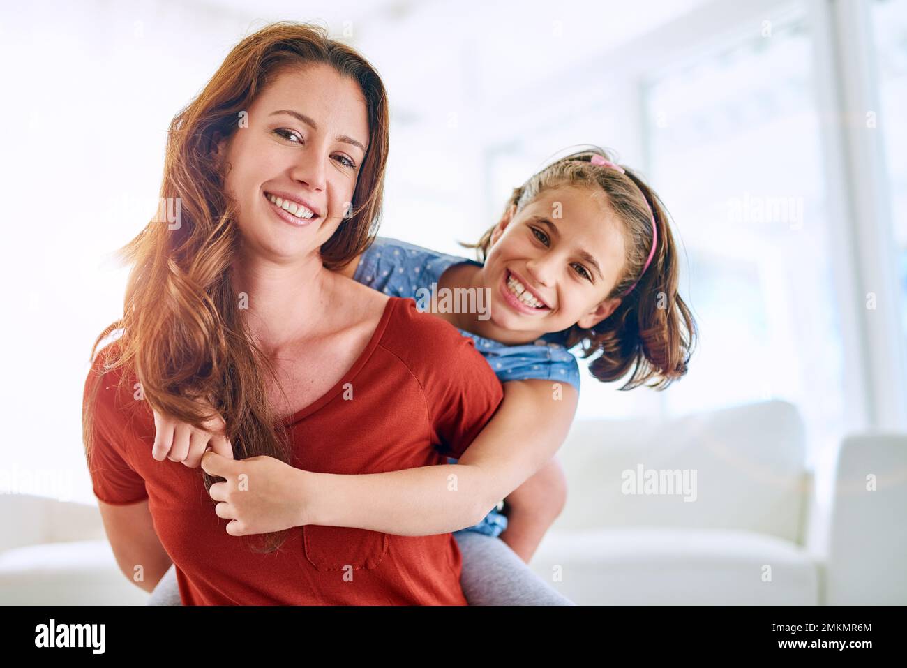 Schöne gemeinsame Momente genießen. Porträt einer Mutter, die ihre Tochter zu Hause mit dem Huckepack mitnimmt. Stockfoto