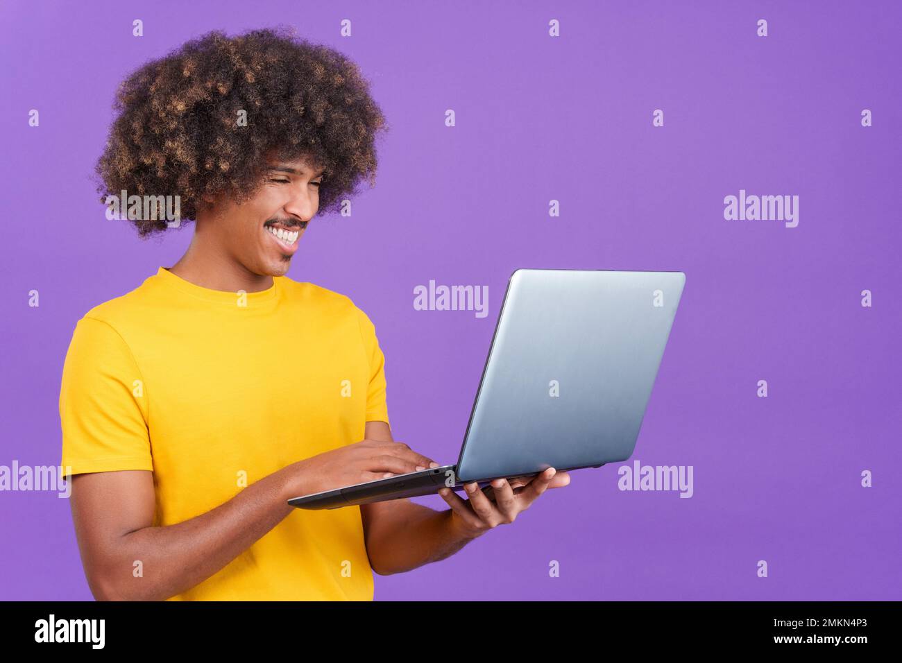 Glücklicher afrikaner, der steht und ein Notebook benutzt Stockfoto