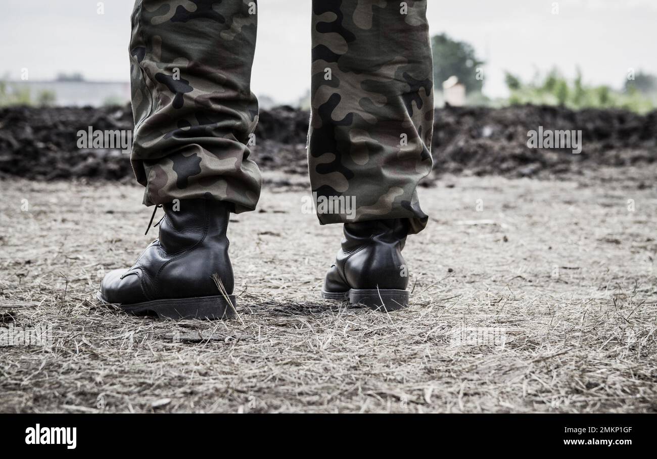 Soldatenbeine auf einem Schlachtfeld, Militärstiefel und Camouflage-Hosen. Stockfoto