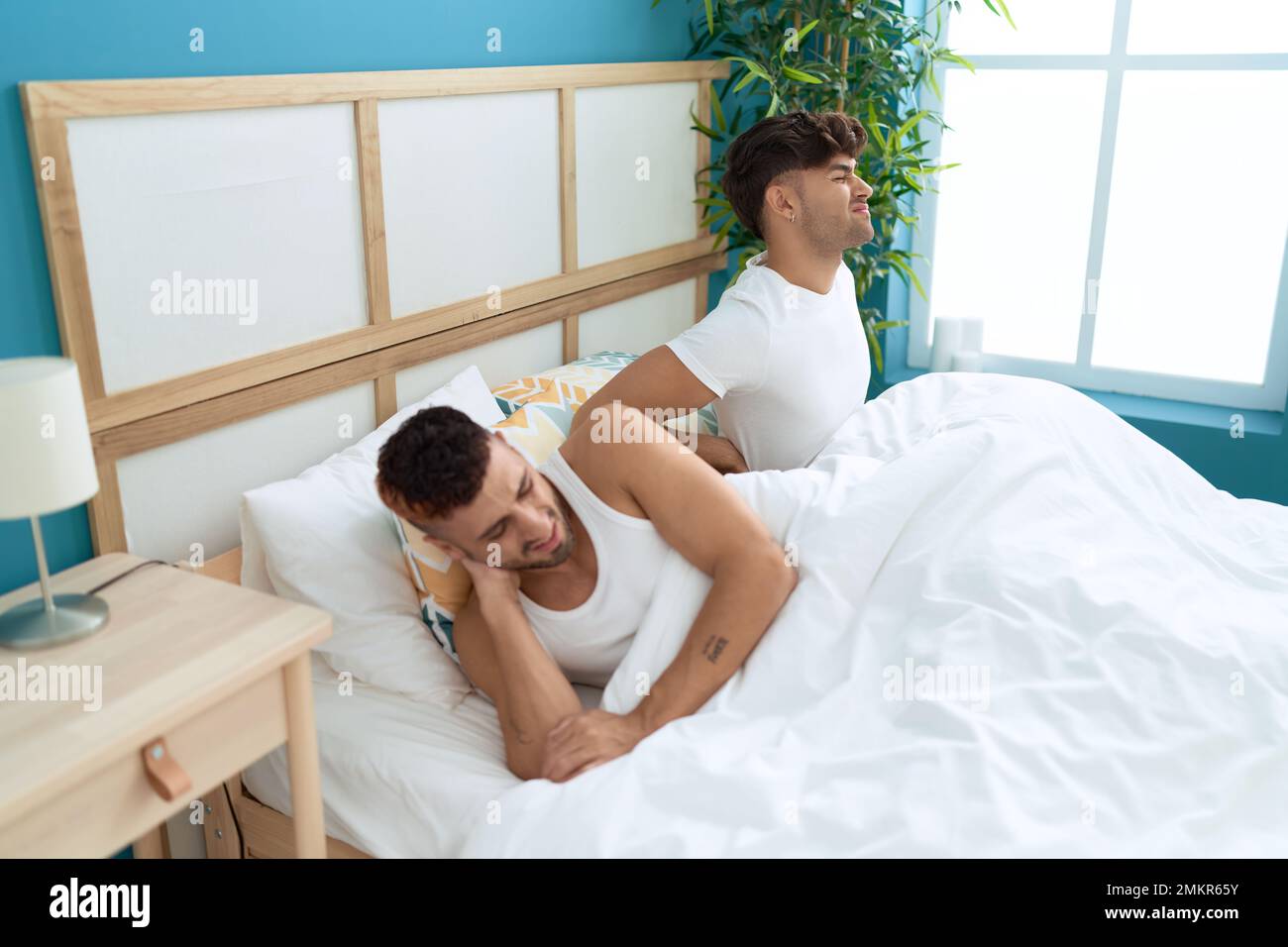 Zwei hispanische Männer, die unter Rückenverletzungen leiden, sitzen im  Bett im Schlafzimmer Stockfotografie - Alamy