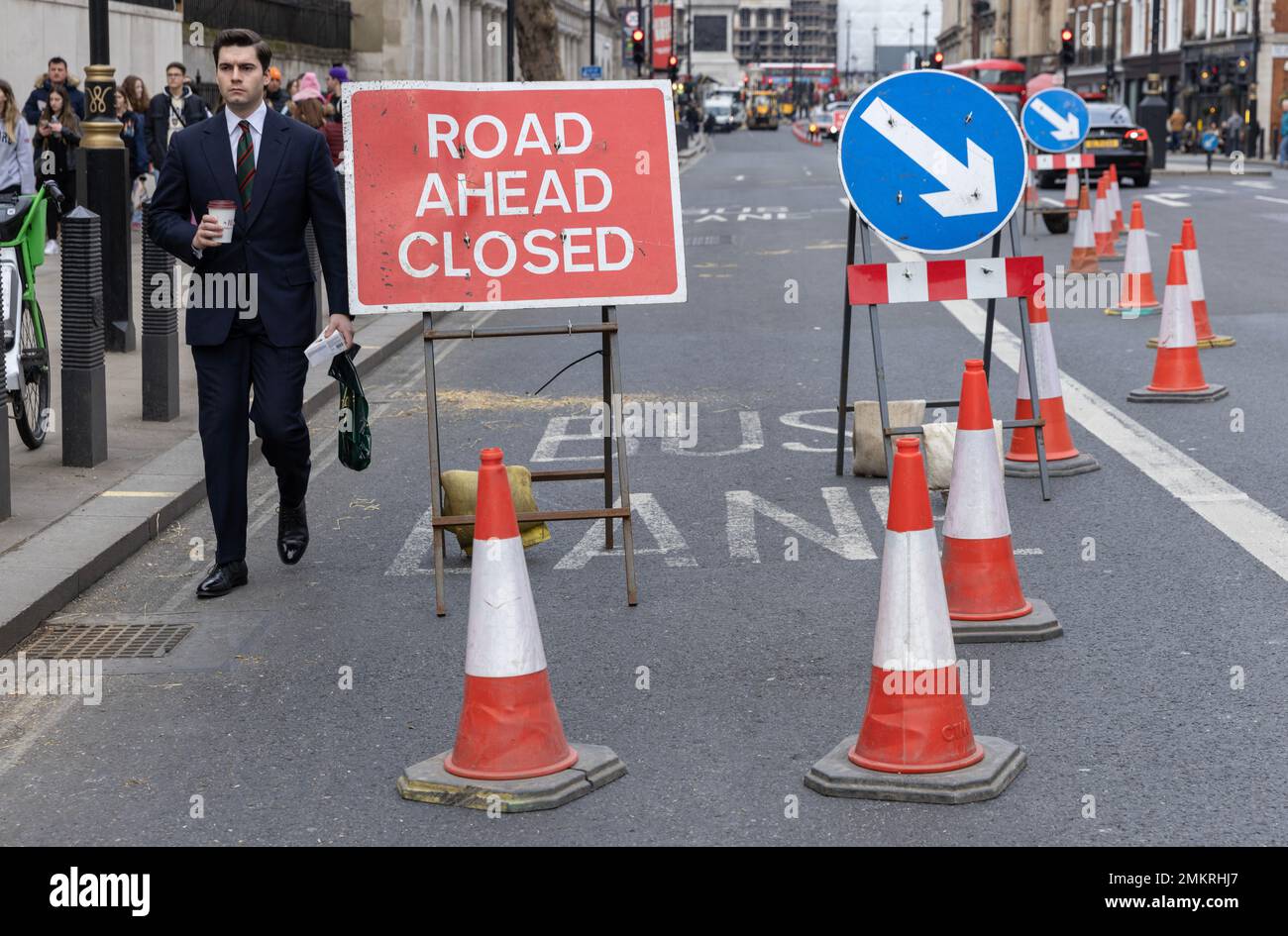 Ein Geschäftsmann navigiert selbst durch Verkehrskegel bei einer Straßensperrung im Zentrum von London, England, Großbritannien Stockfoto