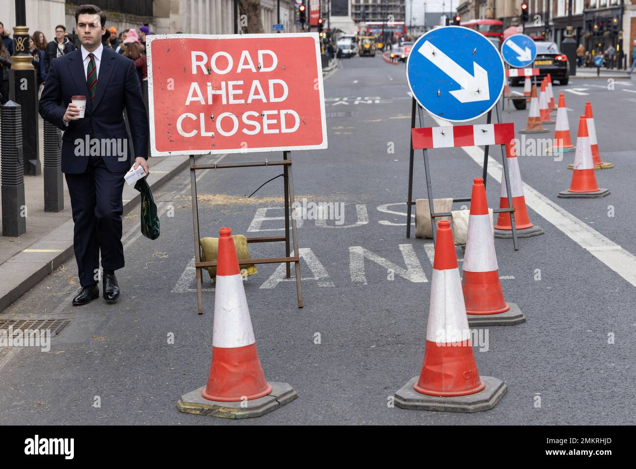 Ein Geschäftsmann navigiert selbst durch Verkehrskegel bei einer Straßensperrung im Zentrum von London, England, Großbritannien Stockfoto
