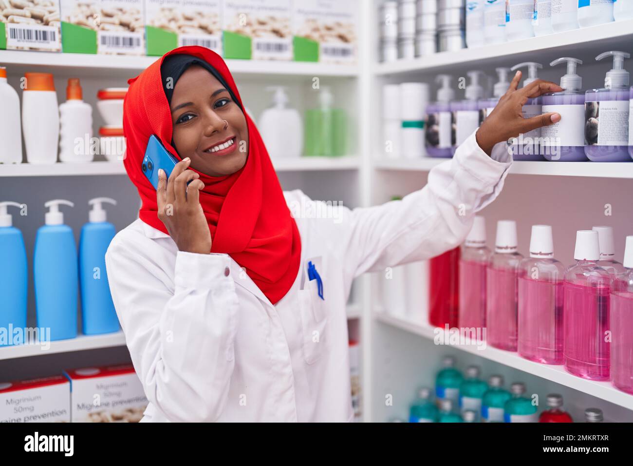 Junge schöne Frau Apotheker im Gespräch auf dem Smartphone in der Apotheke Stockfoto