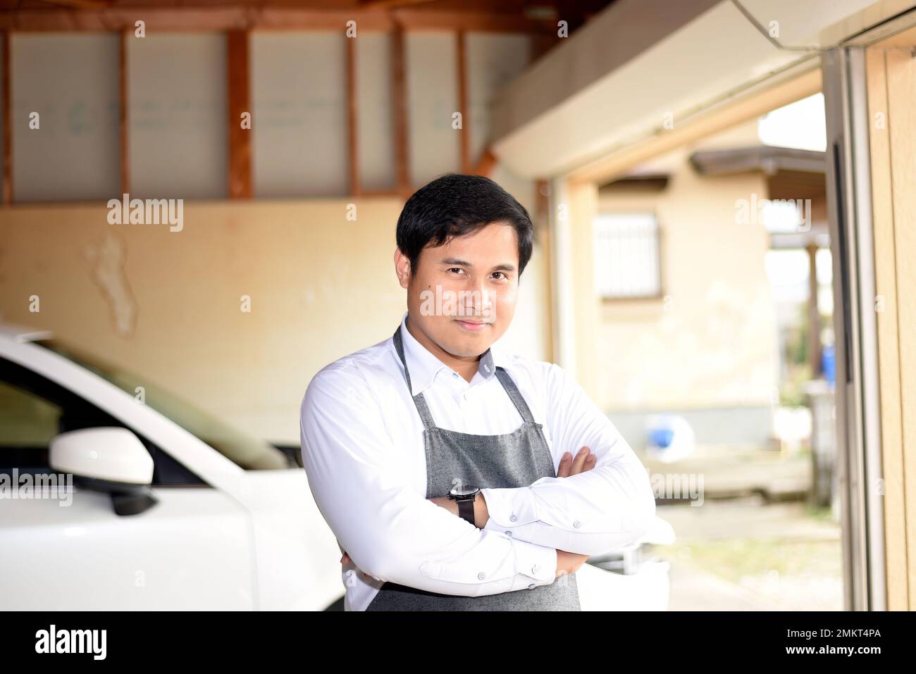 Ein Mann, der eine Schürze am Garagenkreuz trägt Stockfoto