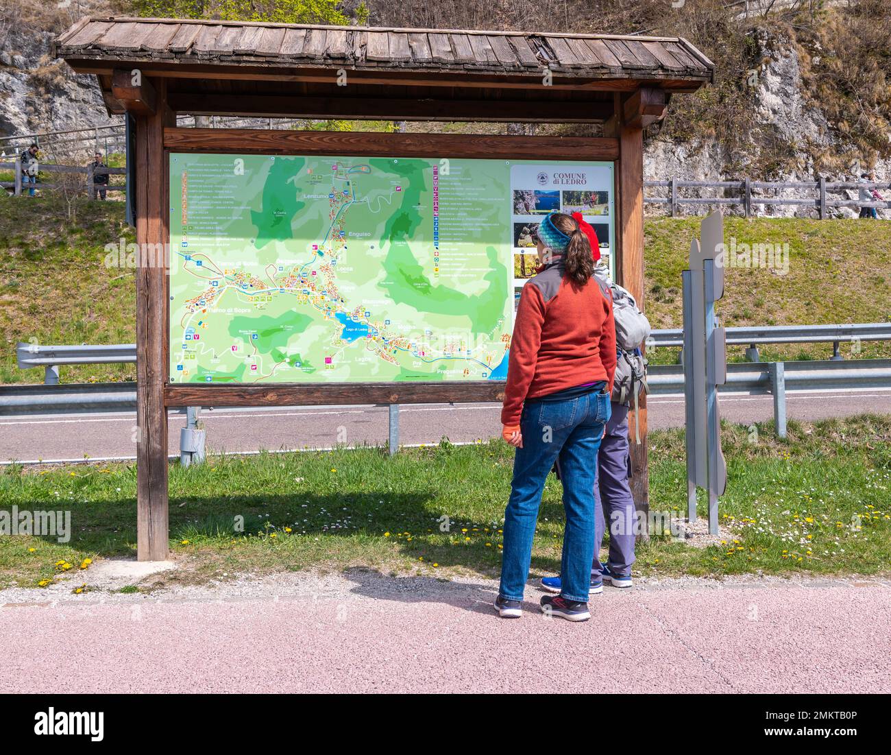 Zwei Touristen, die an einem sonnigen Tag im Frühling am Ledro-See, Ledro-Tal, Provinz Trient, Trentino Alto Adige, Italien, auf die Informationstafel schauen Stockfoto