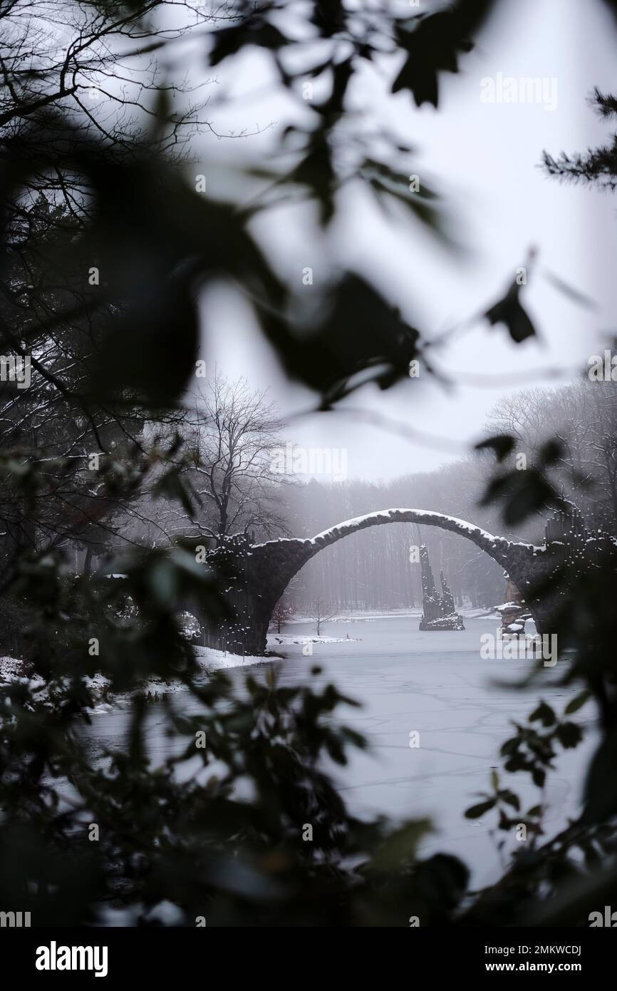 Mittelerde im Winter: Eine alte Steinbrücke über einem gefrorenen See Stockfoto