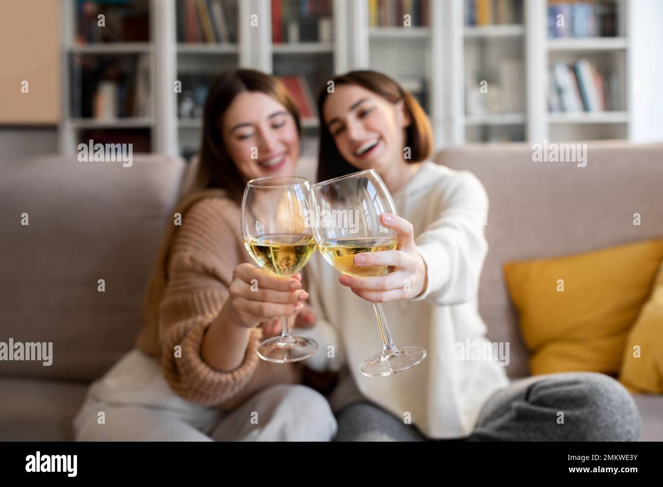 Fröhliche, hübsche europäische Millennials in Pullover jubeln Gläser Wein an, genießen Sie Entspannung und Freizeit Stockfoto