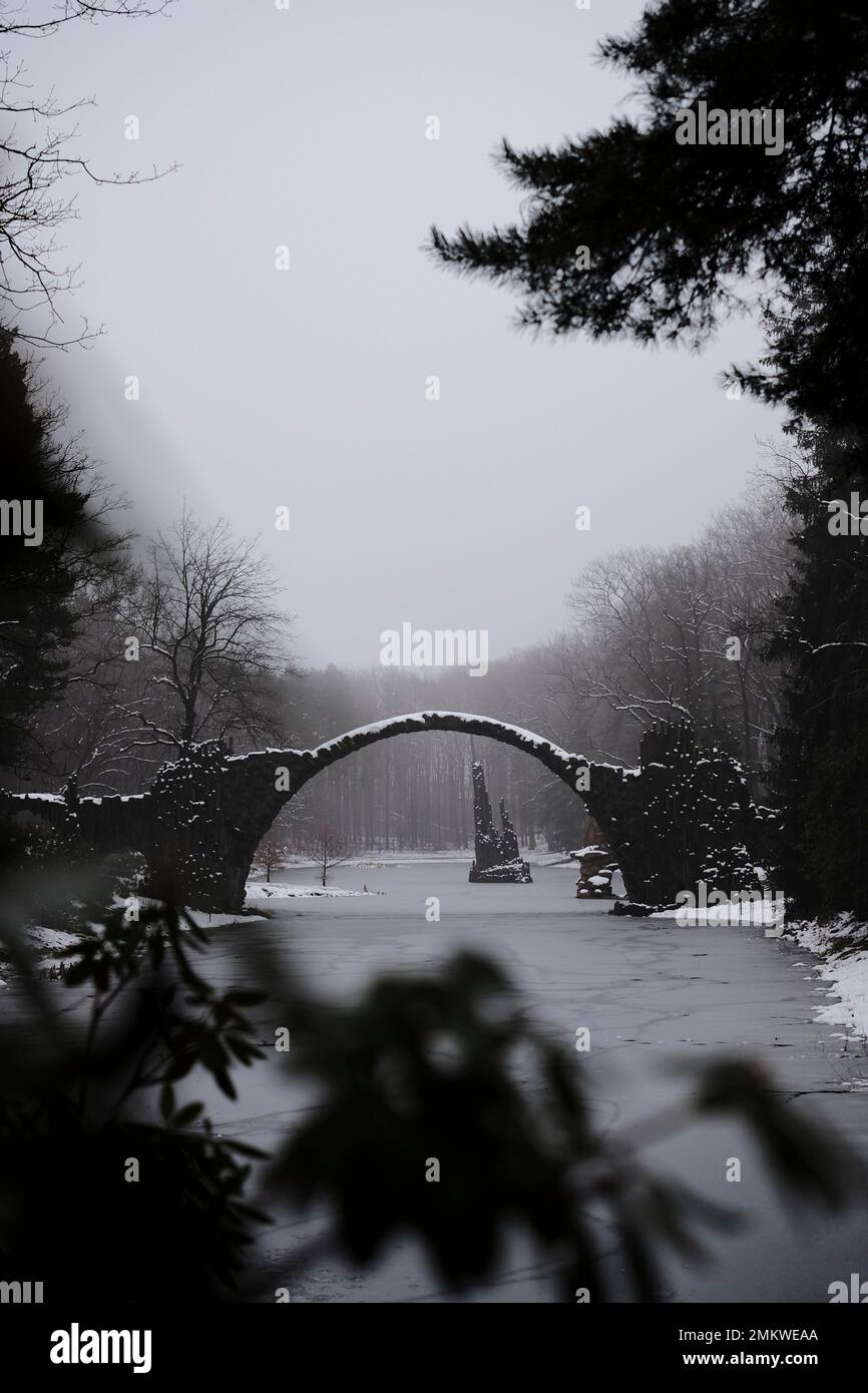 Mittelerde im Winter: Eine alte Steinbrücke über einem gefrorenen See Stockfoto