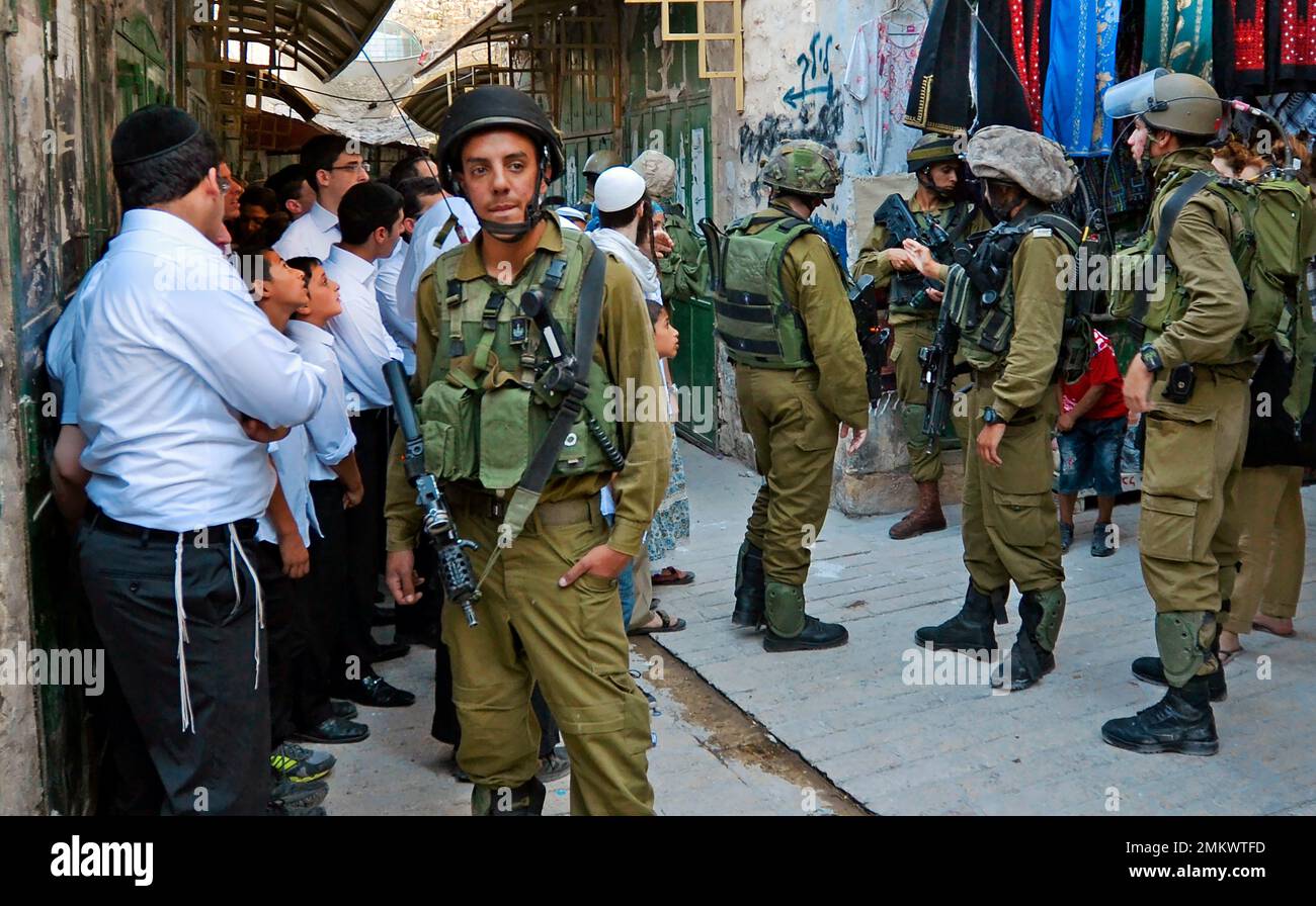 Israelische Siedler, die die Altstadt von Hebron unter Begleitung von Soldaten besuchen Stockfoto