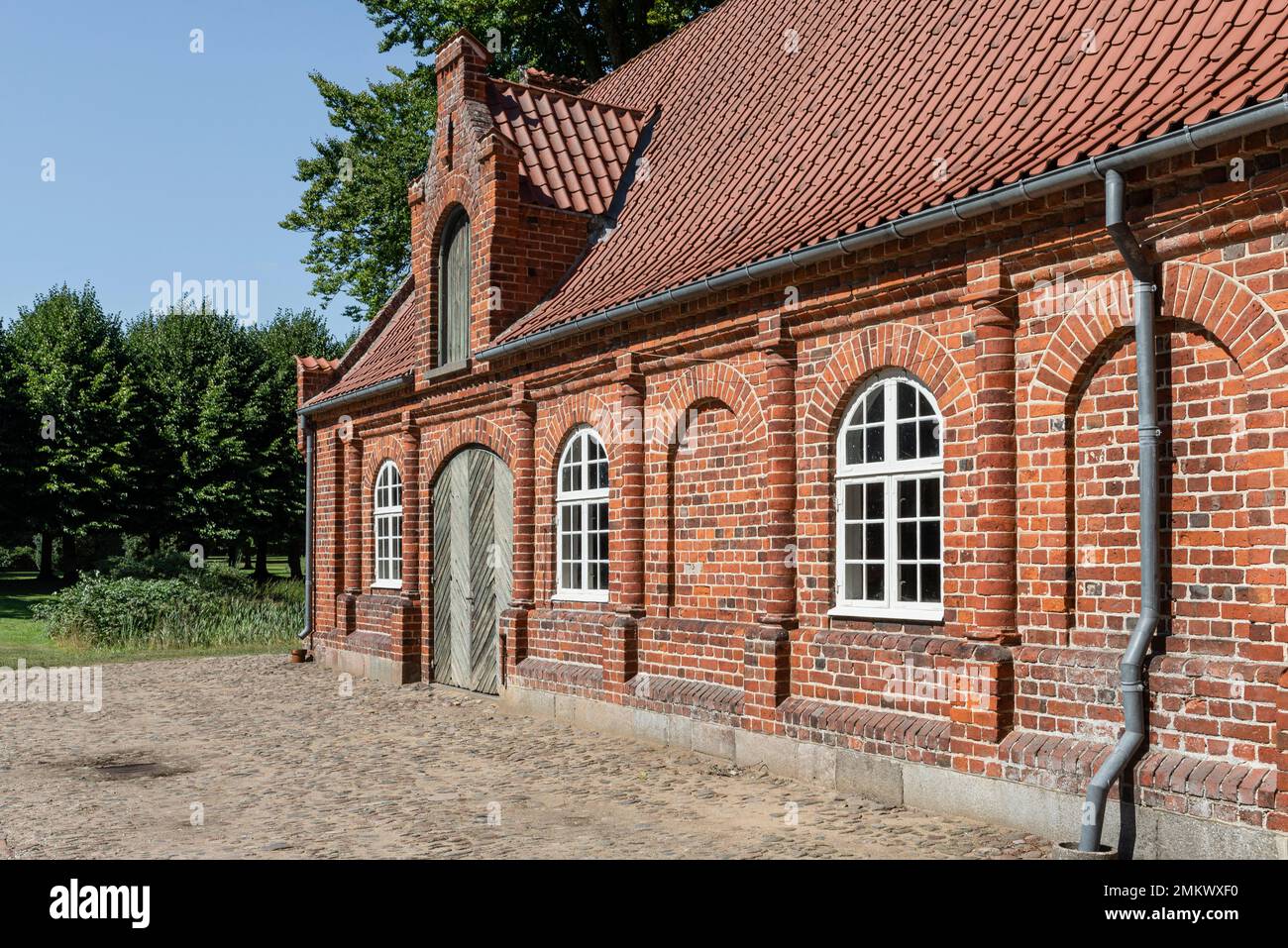 Rote Backsteinfassade der alten Ställe im Garten von Schloss Rosenholm, Jütland, Dänemark Stockfoto