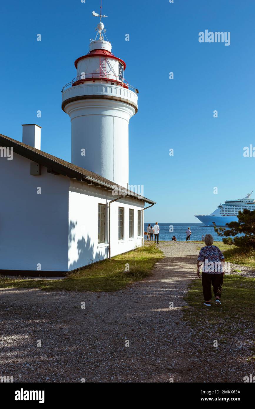 Menschen, die ein Kreuzfahrtschiff am Leuchtturm Sletterhage Fyr auf der Halbinsel Helgenæs in Djursland im Sonnenschein, Jütland, Dänemark, vorbeifahren sehen Stockfoto