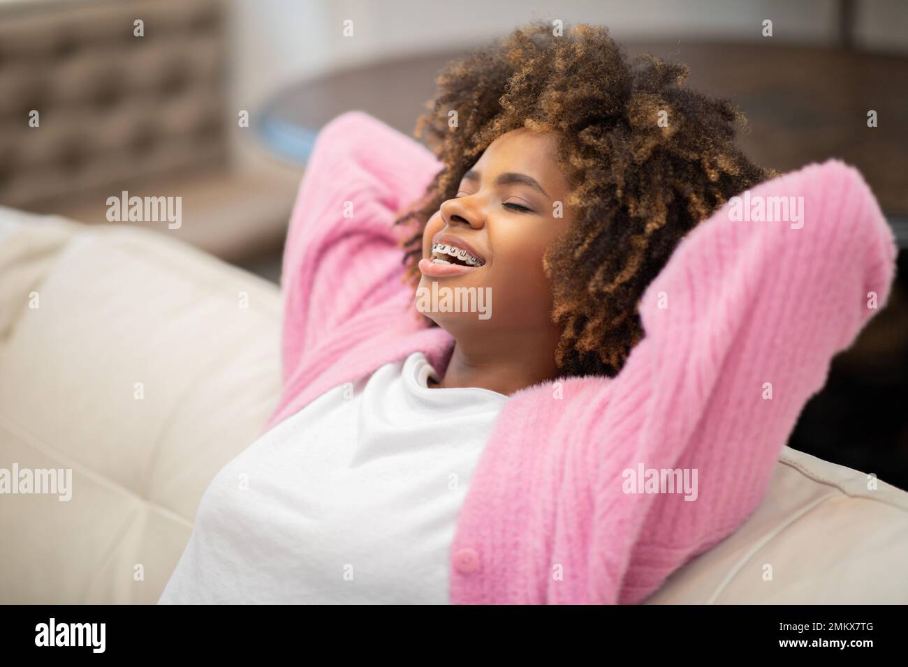 Entspannte junge schwarze Frau, die zu Hause auf der Couch chillt Stockfoto