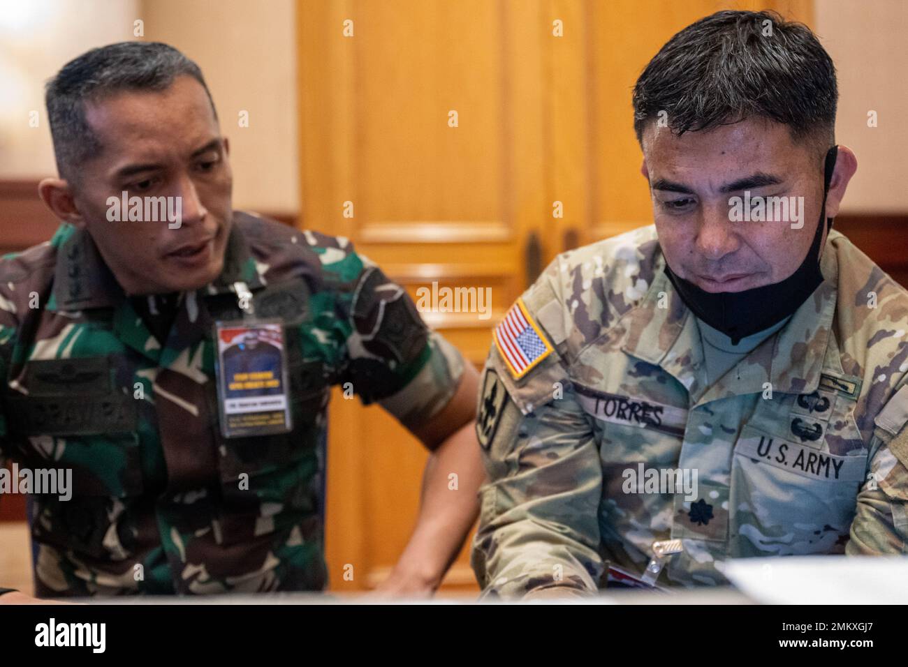 Ein Mitglied der Tentara Nasional Indonesia (TNI, Indonesische Streitkräfte) beobachtet Oberstleutnant Brandon Torres von der Hawaii National Guard, während er während der Übung Gema Bhakti 2022, 12. September 2022, über fiktive Geheimdienstberichte geht. GEMA Bhakti 22 ist ein gemeinsames Übungsprogramm des US-Indo-Pacific Command, bei dem die Vereinten US-Streitkräfte und die TNI-Streitkräfte zusammenarbeiten, um die Interoperabilität zu erhöhen und die regionale Stabilität und Sicherheit durch bilaterale und multilaterale Partnerschaften zu verbessern. Stockfoto