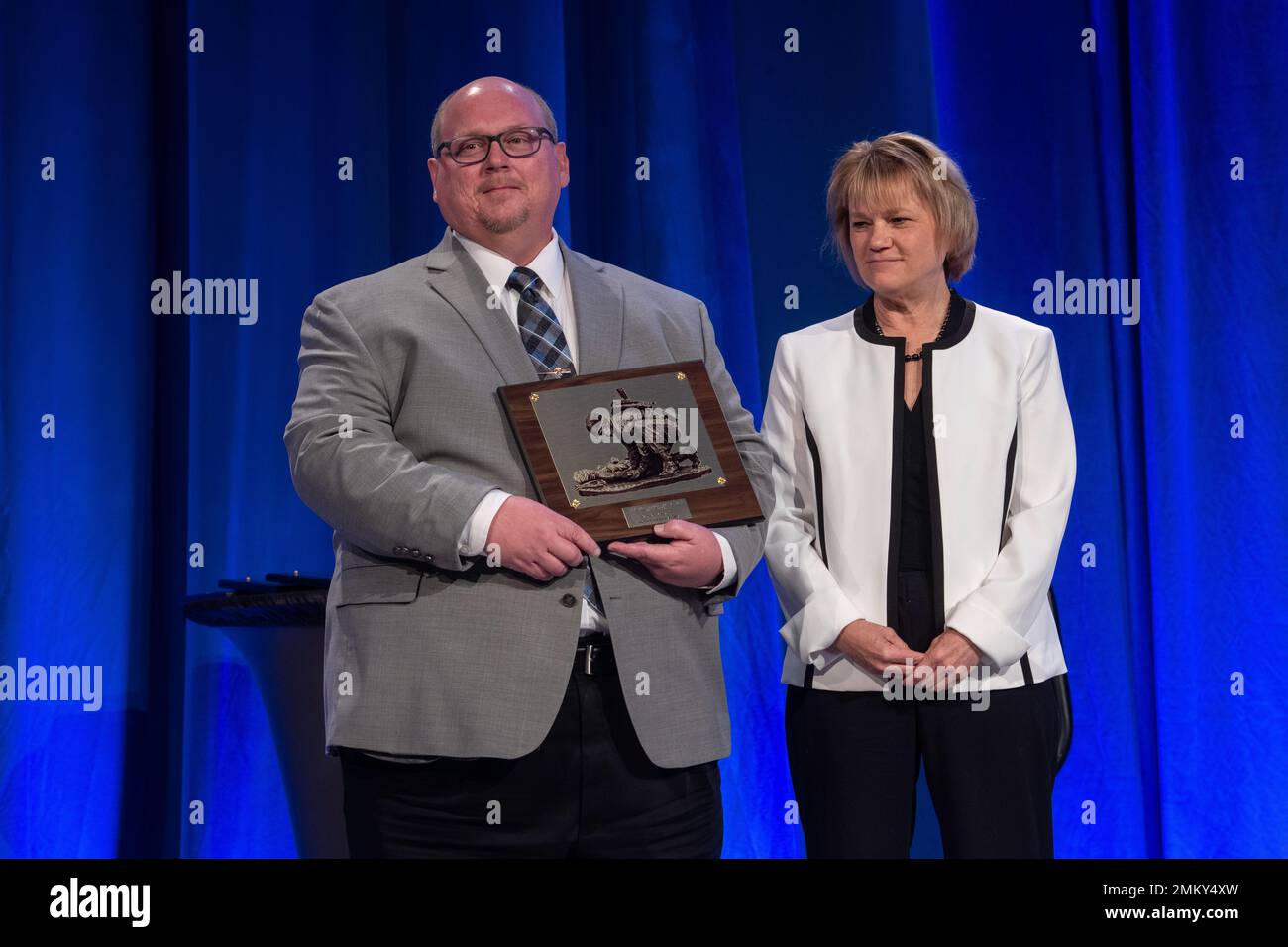 Herr Fred Brozoski nimmt den Distinguished Service Award von Frau Seileen Mullen, der amtierenden Verteidigungsministerin für Gesundheitsangelegenheiten, an. MHSRS bietet eine kollaborative Umgebung für den Informationsaustausch zwischen militärischen Anbietern mit Einsatzerfahrung, Forschung und akademischen Wissenschaftlern, internationalen Partnern und der Industrie über Forschung und damit zusammenhängende Gesundheitsinitiativen, wie z. B. Combat Casualty Care, Operational Medicine, Clinical and Rehabilitative Medicine, Medical Simulation and Information Sciences und Infektionskrankheiten. Stockfoto