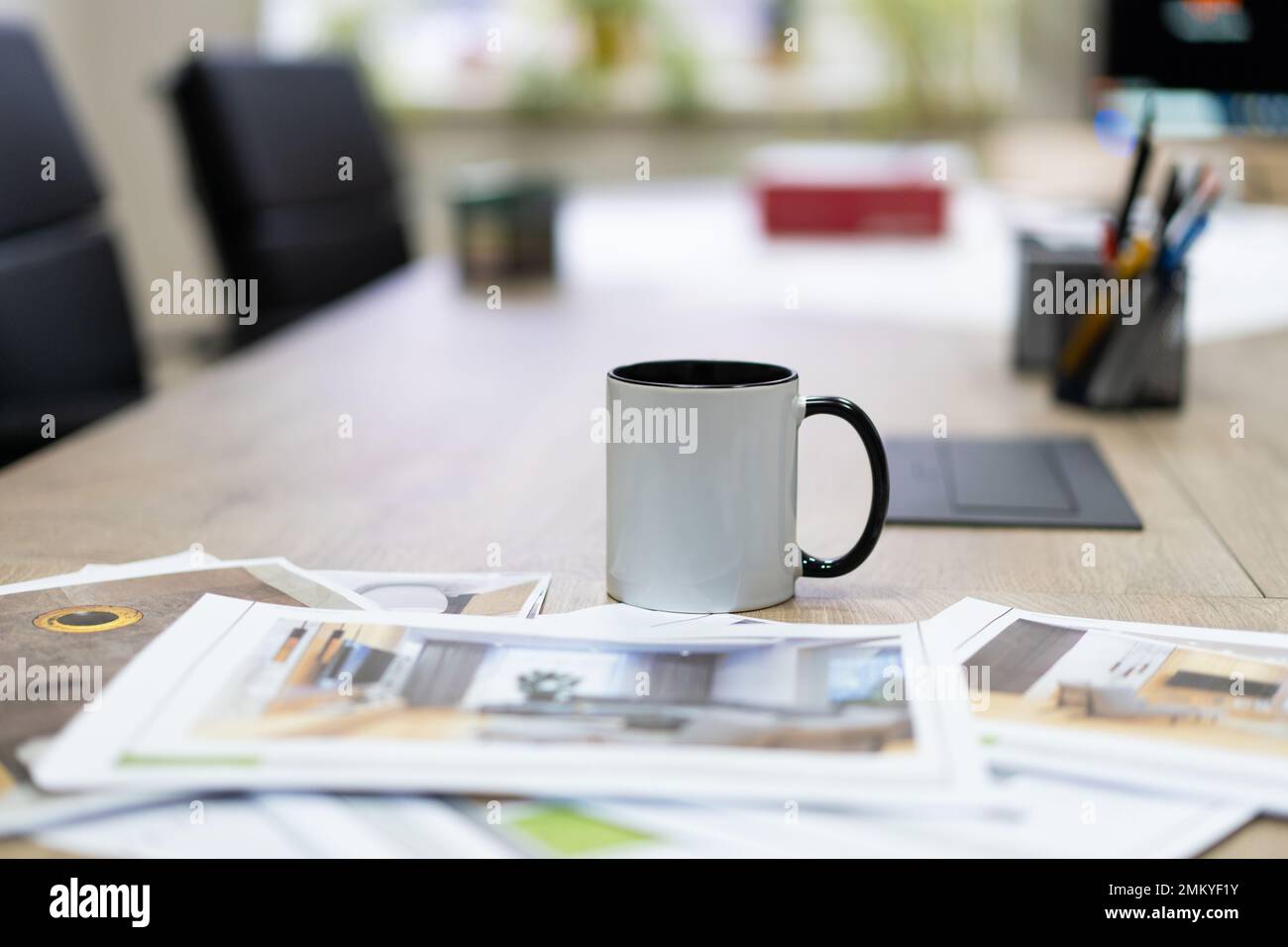 Gedruckte Fotozeichnungen von Innenprojekten auf dem Tisch und eine Tasse Tee Stockfoto