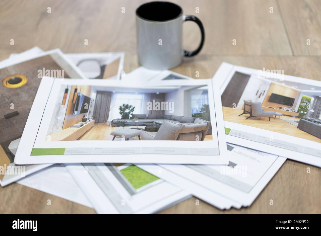 Gedruckte Fotozeichnungen von Innenprojekten auf dem Tisch und eine Tasse Tee Stockfoto