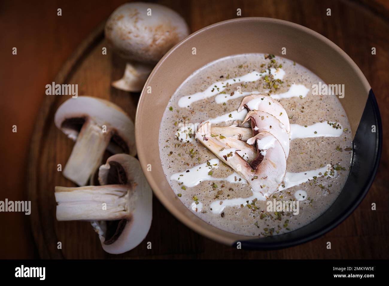 Pilzcremesuppe aus Champignons mit Gewürzen, auf einem Holzbrett Stockfoto
