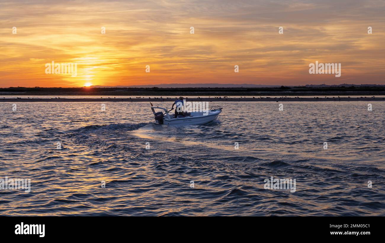 Isla Cristina, Provinz Huelva, Andalusien, Südspanien. Motorbetriebenes Außenbordboot vor dem Himmel bei Sonnenuntergang. Stockfoto